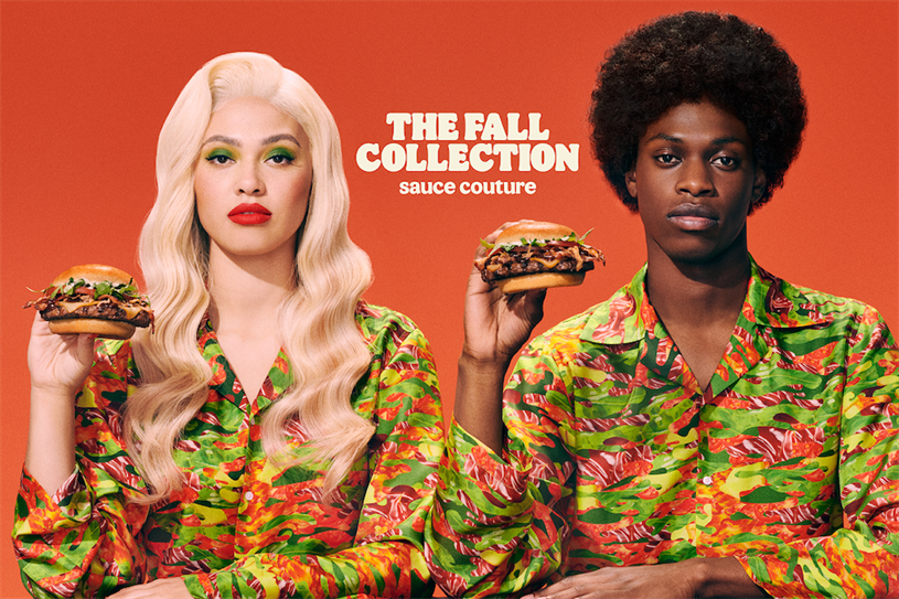 A man and a woman sit next to each other, each holding a burger. The writing on the poster reads: "The fall collection, sauce couture".