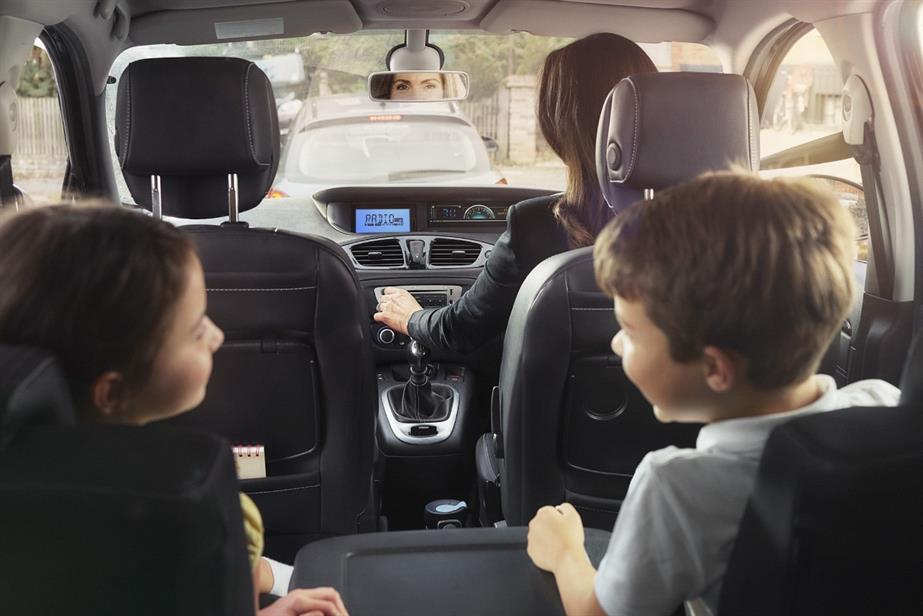 Two children and their mum listen to the radio in their car