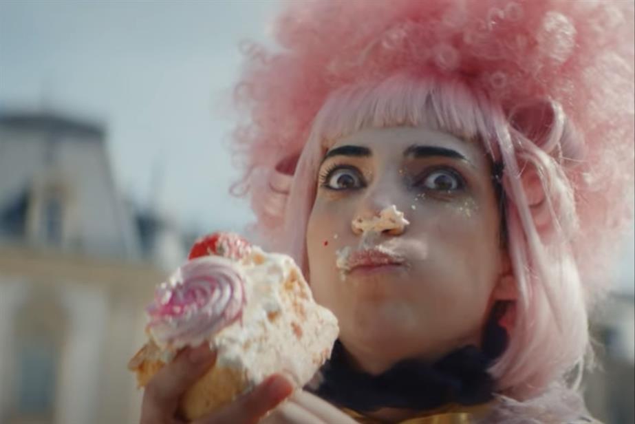 Woman in large wig eating cake