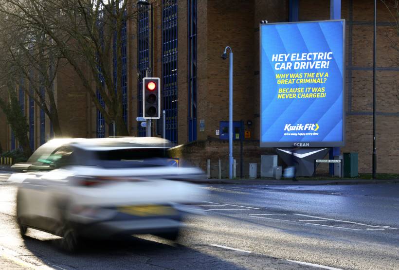 Outdoor advertising for Kwik fit by road with car going by