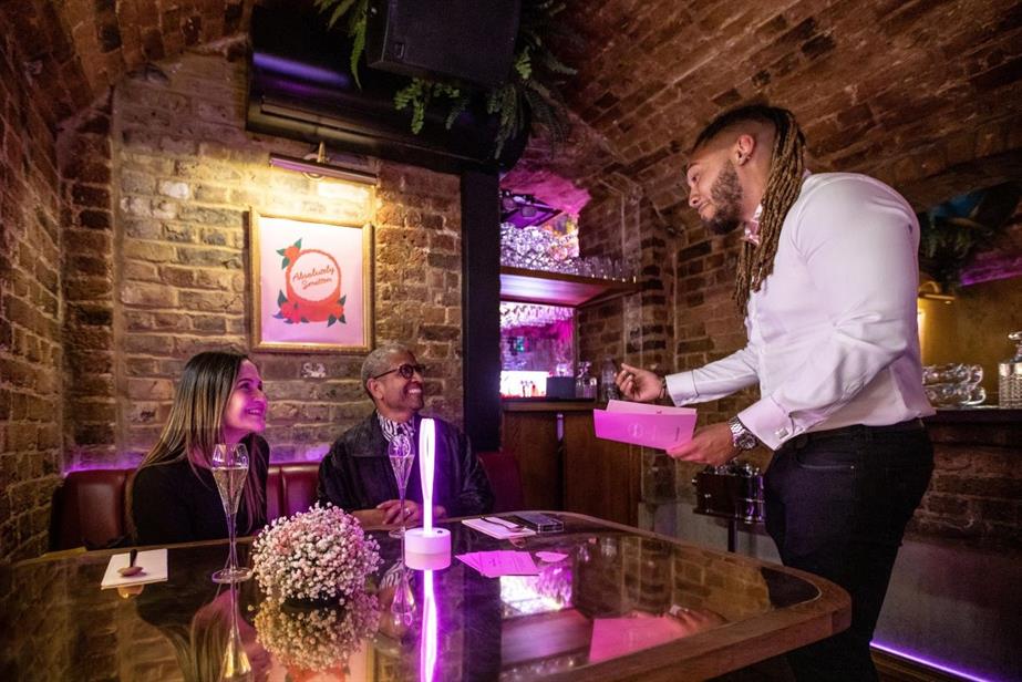 A waiter explaining the menu to a smiling couple 