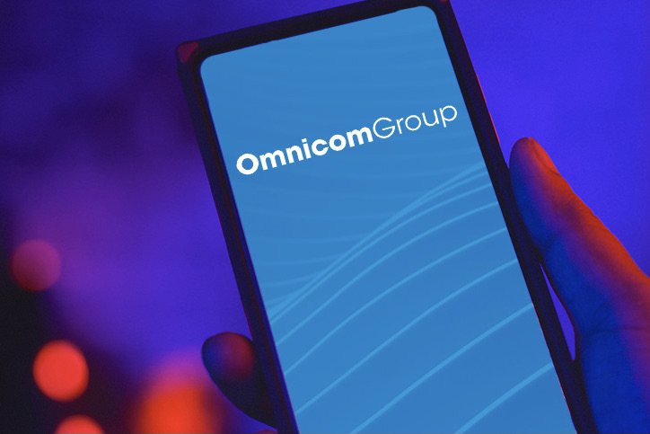 A hand holding a screen with the omnicom logo