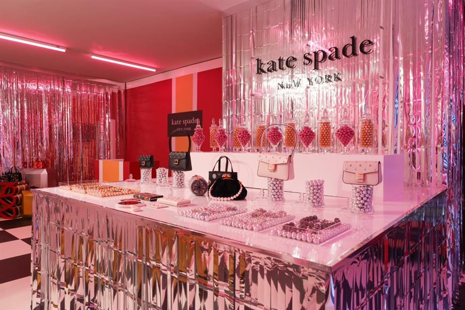 A display of jewellery and handbags, with the Kate Spade New York logo in the background.