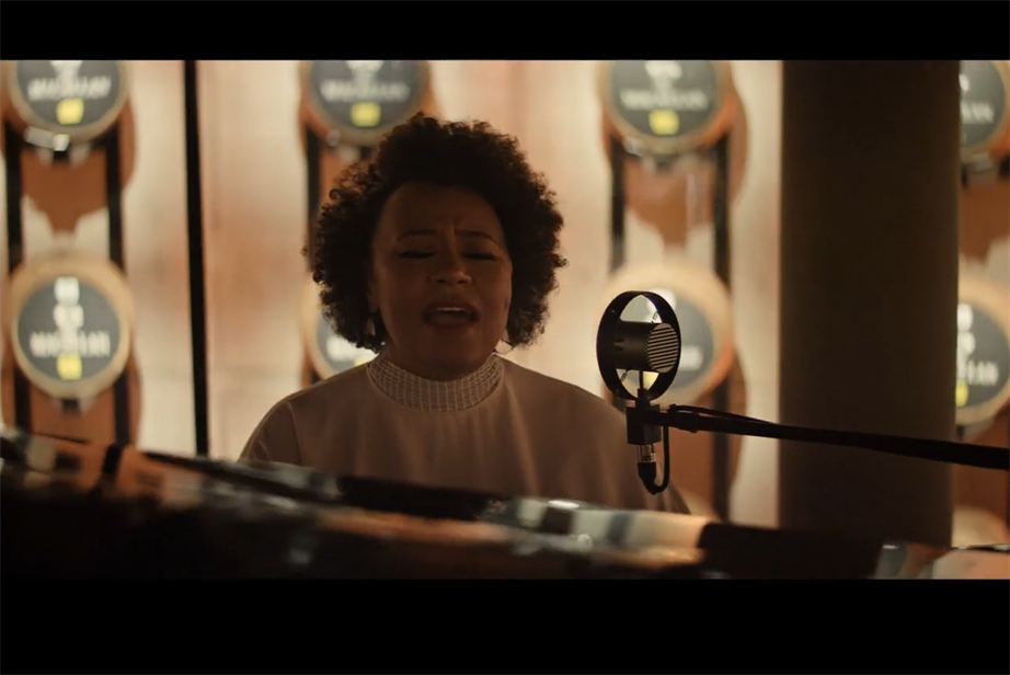Screenshot from film showing a woman singing at a piano