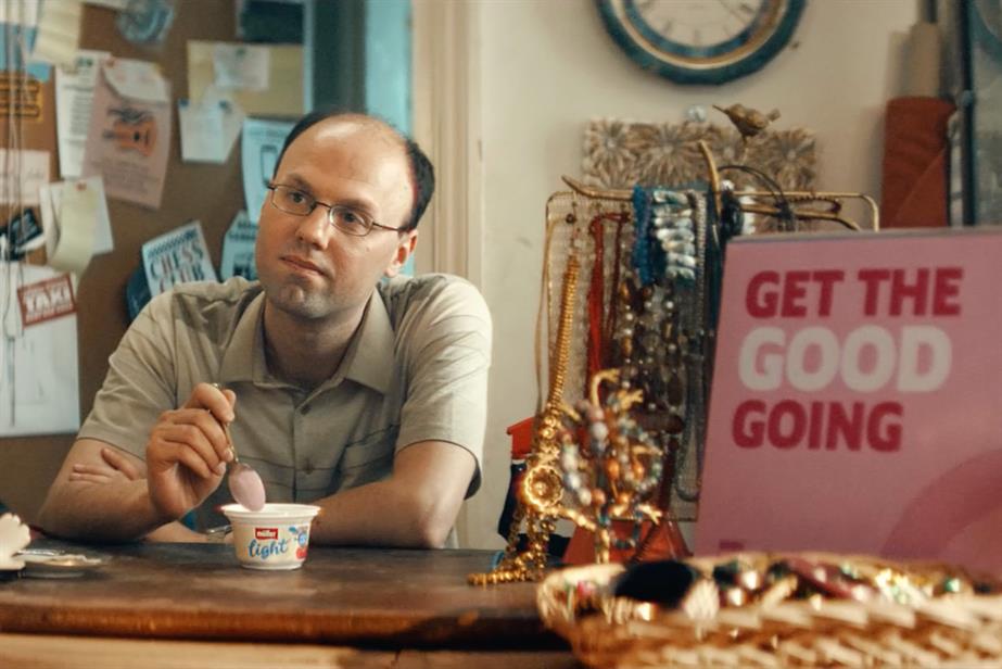 a balding man eats from a pot of Muller Light and dreams of a better life