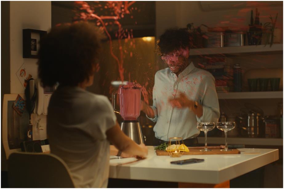 An exploding blender covers a man standing in his kitchen with pink liquid