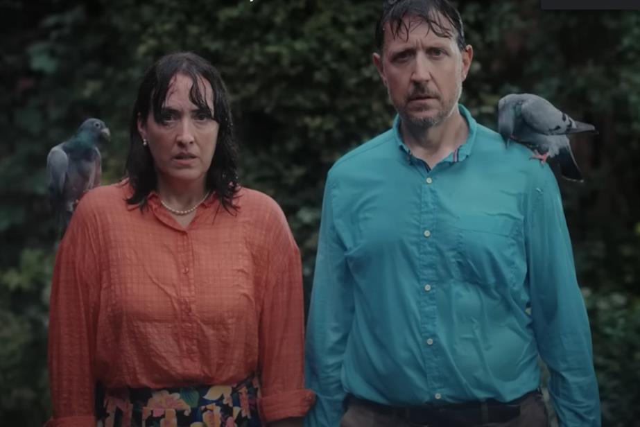 Couple standing in the rain with pigeons on their shoulders