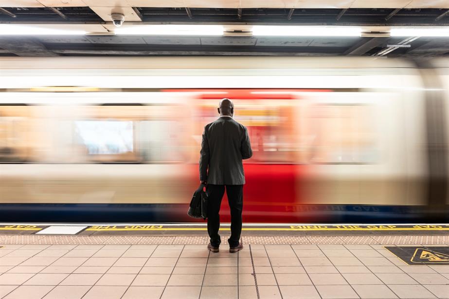A man stands on the platform as a tube travels past