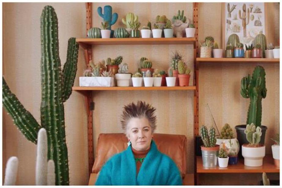 A woman with spiky hair sits surrounded by spiky cactuses