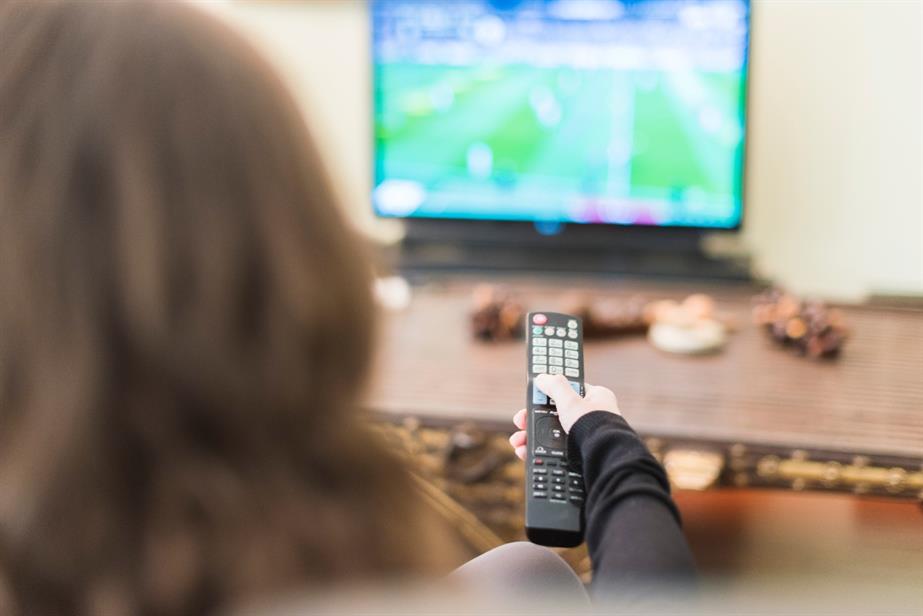 A woman watches sport on TV.