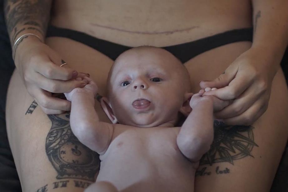 A baby on the lap of a woman in underwear