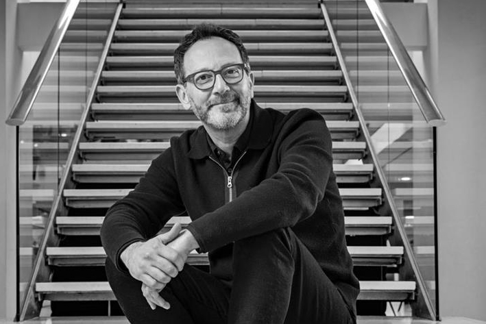 Zaid Al-Qassab, group chief executive of M&C Saatchi, sitting on some stairs and smiling