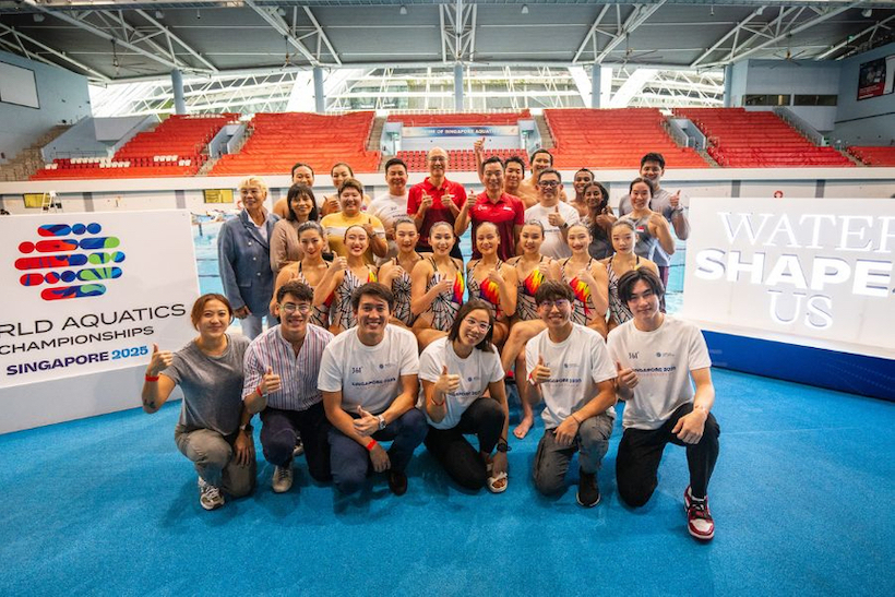 Group of people pose in the World Aquatics Championships arena