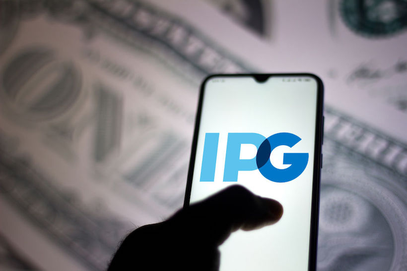 Hand holding smart phone displaying IPG logo