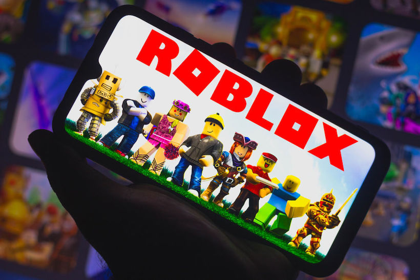 Hand holding smart phone with Roblox app on screen