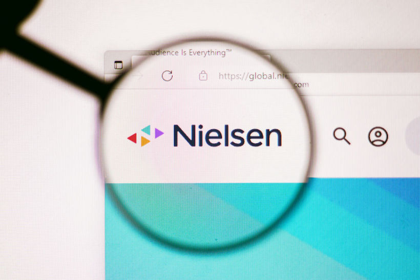 The homepage of the Nielsen Holdings website seen on a computer screen through a magnifying glass