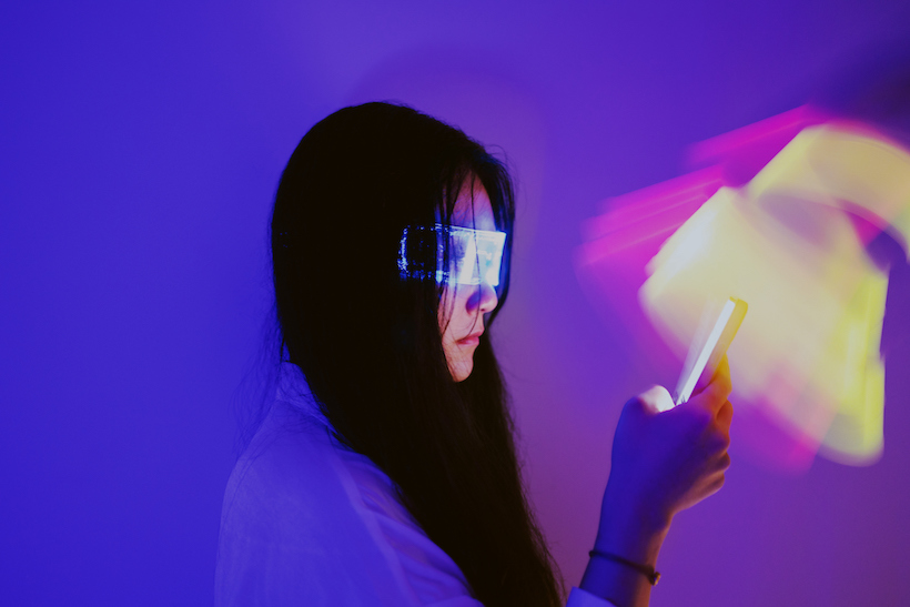 Woman wearing augmented reality glasses holding smartphone, metaverse concept