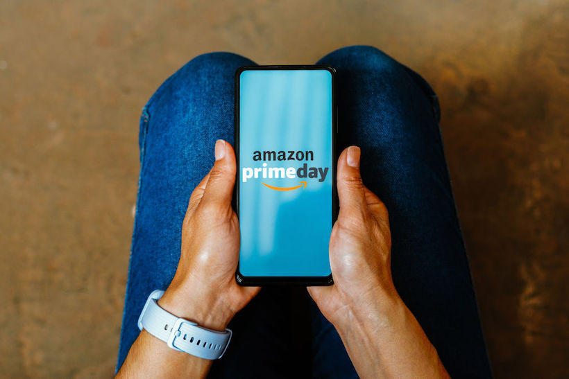 Person holding smart phone displaying Amazon Pride Day logo