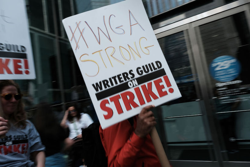 Members of the Writers Guild of America (WGA) East hold signs as they walk in the picket-line outside of HBO and Amazon's offices