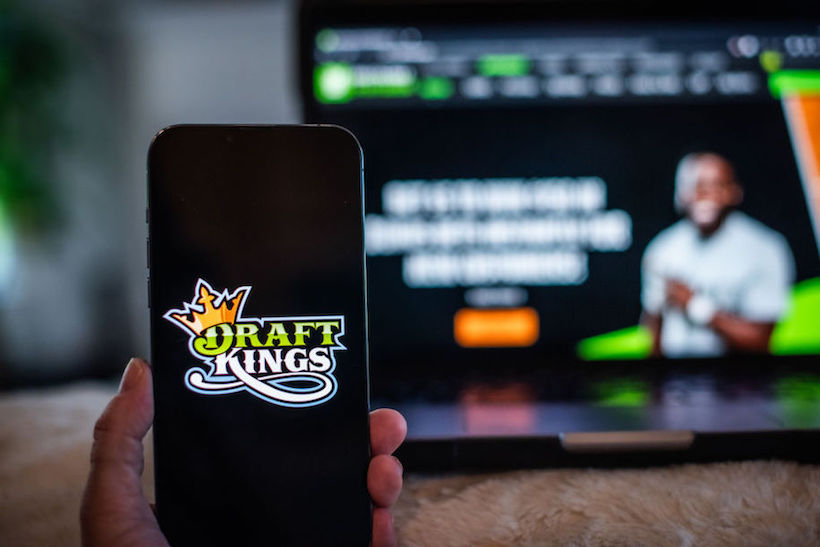 Hand holding smart phone displaying DraftKings screen