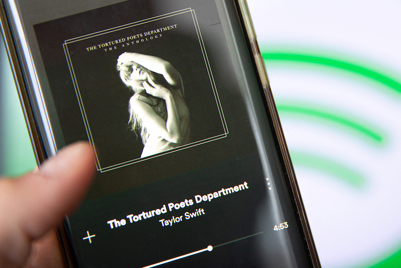 Hand holding smart phone playing Taylor Swift's The Tortured Poets Department