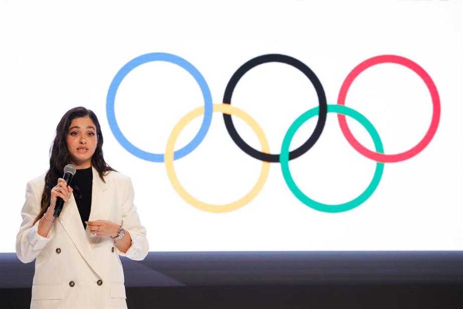 Refugee Olympian Yusra Mardini stands in front of the Olympic logo