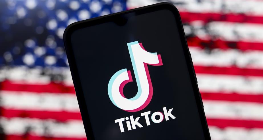 The TikTok logo appears on a smartphone screen with the United States flag in the background