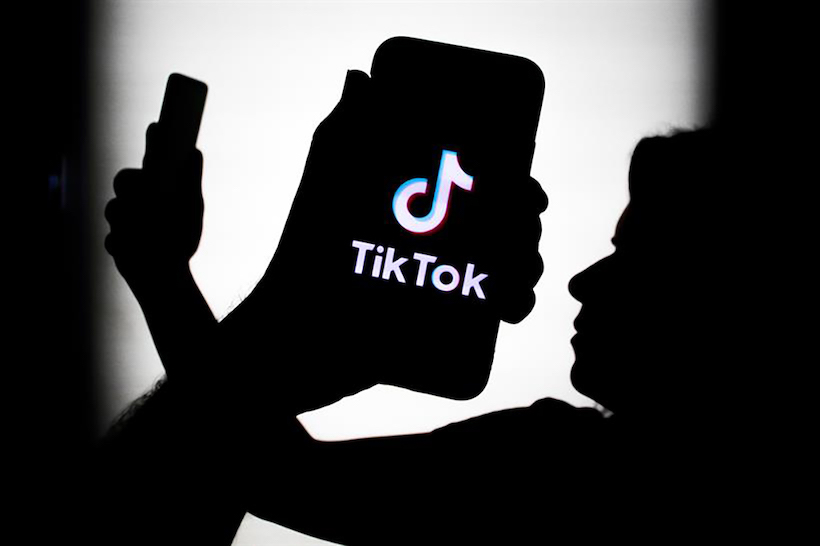 Hand holding smart phone displaying TikTok logo