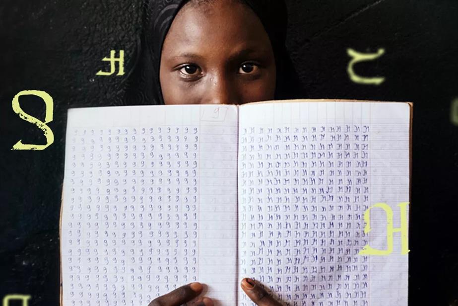 A woman holds a notebook with alphabet symbols