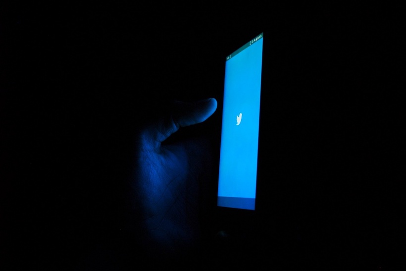 Hand holding smart phone with Twitter logo on screen