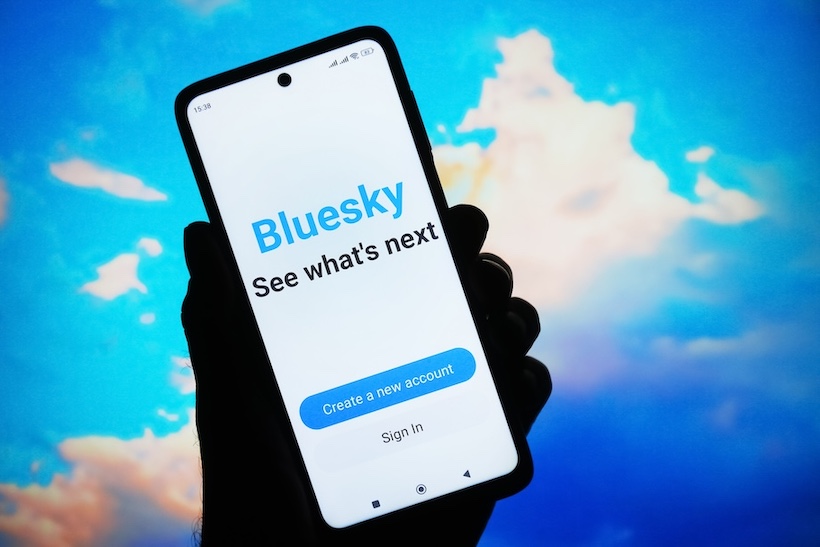 Hand holding smart phone displaying Bluesky app