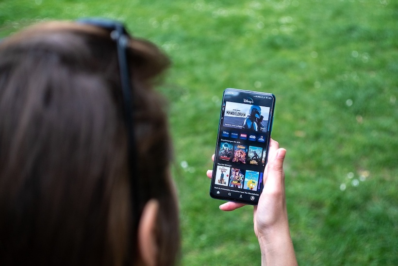 Person holding smartphone with Disney+ app