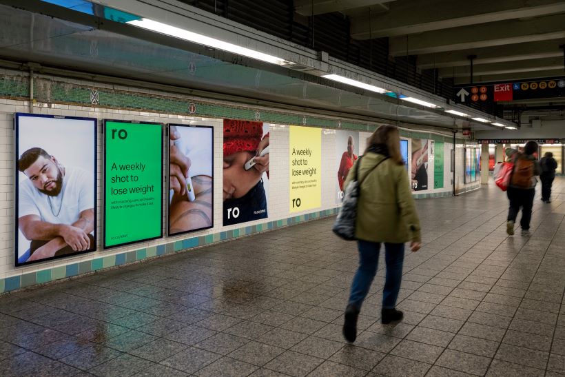 people walking past billboards in subway station