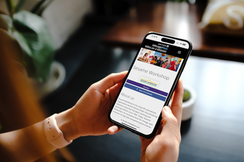 Person holding smart phone displaying Sesame Workshop website