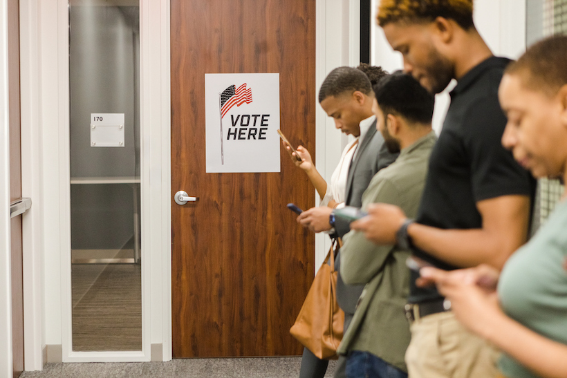 Group of people stand in line at the community center waiting to vote