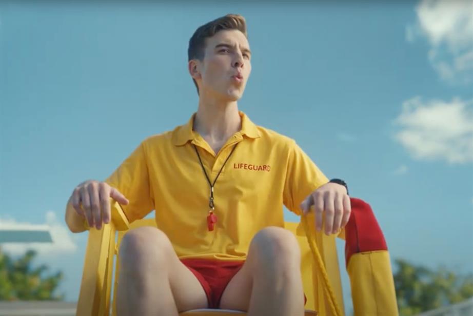 A lifeguard dressed in bright yellow whistles, in an ad for Confused.com