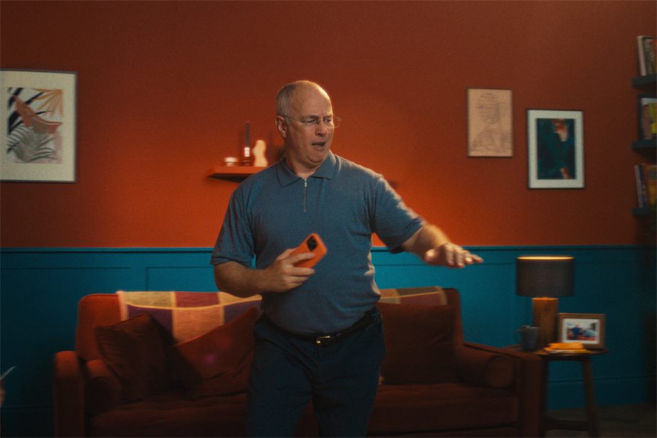 a man dancing in his leaving room with a mobile phone in his hand