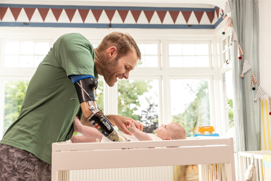 Marine Mark Ormrod MBE changing a baby's nappy