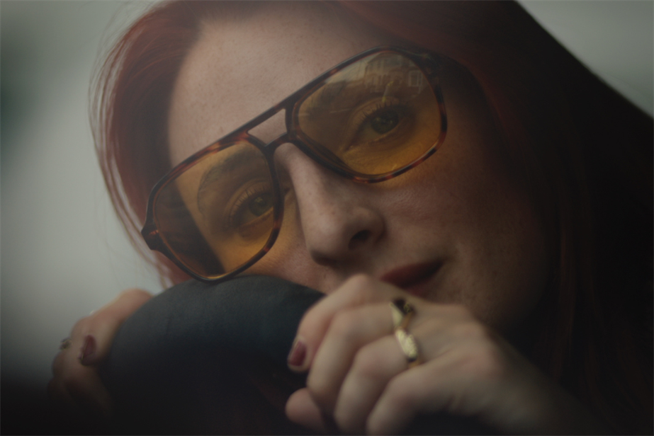 a woman with yellow-tinted sunglasses in a car 