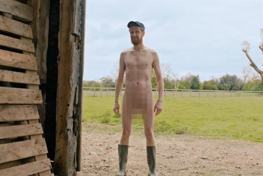 Naked man standing in a barn