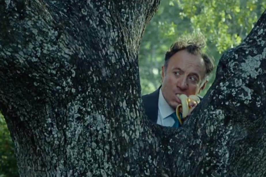 Man hiding behind a tree eating a banana