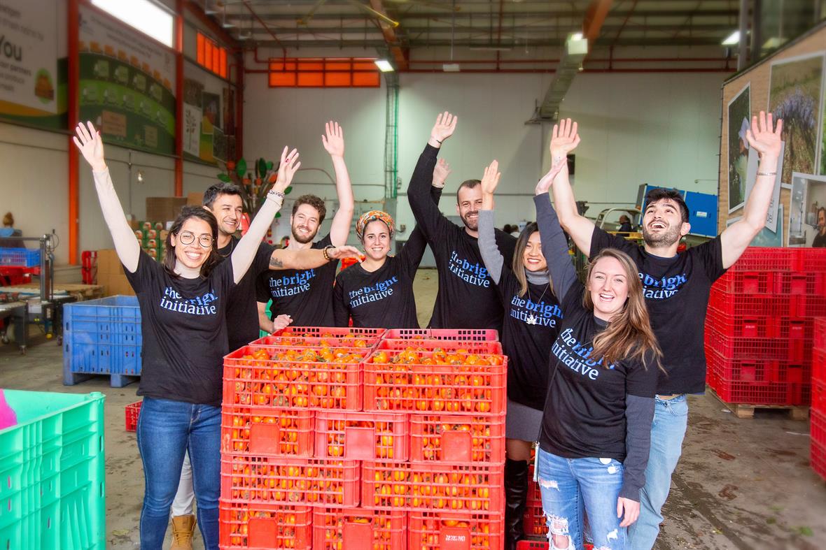 group of people around boxes of oranges - charity initiative