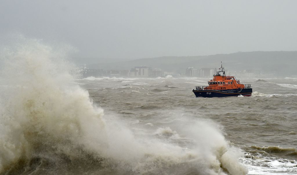 The RNLI Newhaven lifeboat is seen beyond waves as they crash into the sea wall at Newhaven Harbour (Photo by GLYN KIRK/AFP via Getty Images)