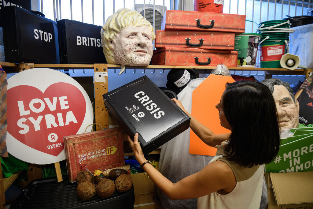 Melanie Kramers of Oxfam holds a "Crisis" briefcase, while surrounded by assorted props used in political campaigns, in the store room at Oxfam's headquarters. Photo: Leon Neal/Getty Images 
