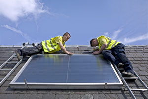 Workmen installing a solar thermal panel after receiving advice from the Energy agency, Ayrshire