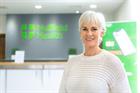 A woman standing in a Nuffield Health office with the Nuffield Health logo in the background