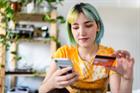 Young woman with colored hair is shopping online with a credit card