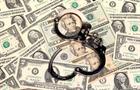 Handcuffs on top of dollar bills, displaying corruption and fraud concept