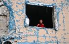 A woman stands in a smashed window inside a residential building damaged as a result of shelling by Russian troops in Sviatoshynskyi district, Kyiv, capital of Ukraine.