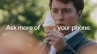 The words "ask more of your phone" are superimposed over a man holding a vanilla ice cream cone